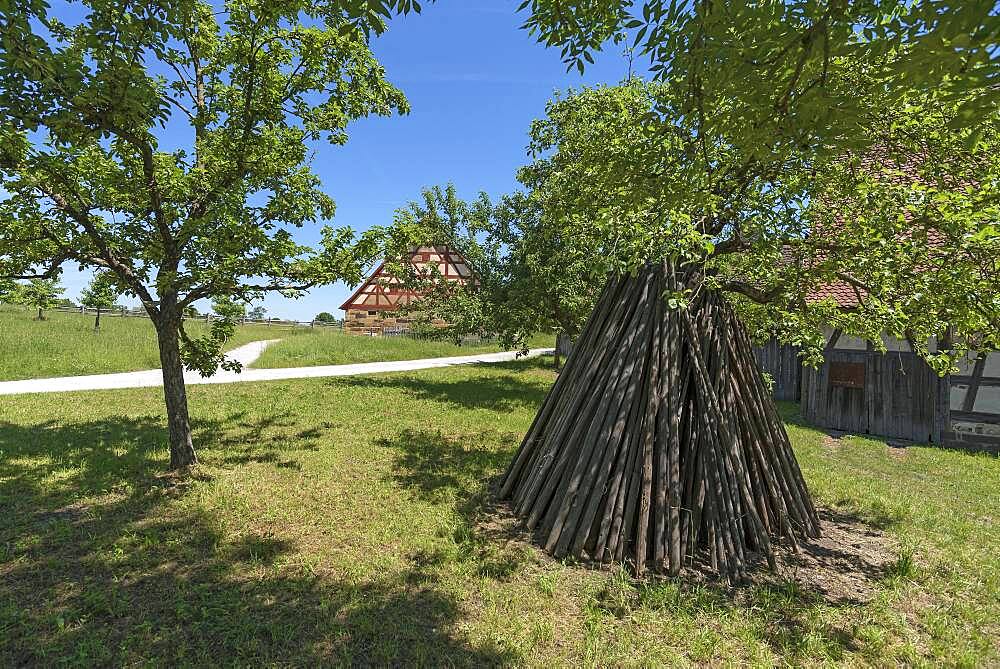 Tent-like arranged wooden poles, behind a historical farmhouse 18th century, Franconian Open Air Museum, Bad Windsheim, Middle Franconia, Bavaria, Germany, Europe