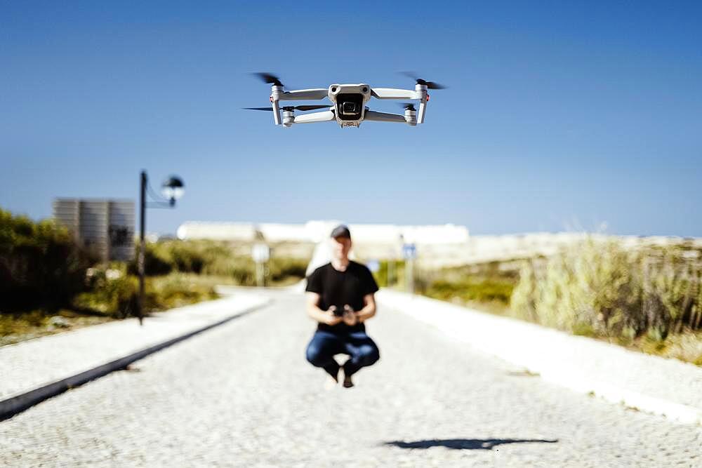 Man holding remote flying together with his drone in first plan