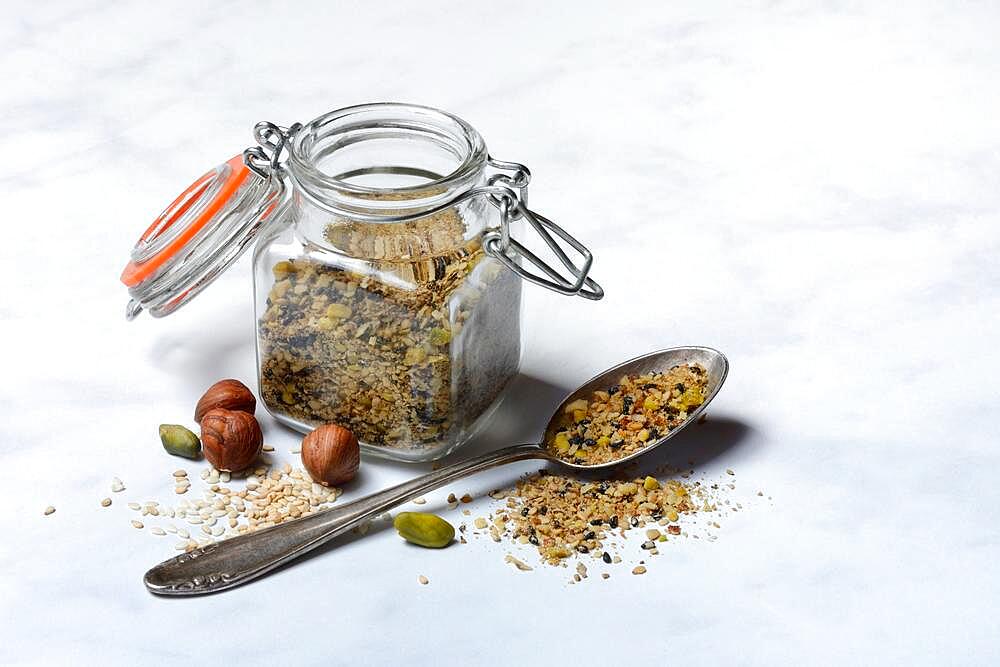 Dukkah, Arabic spice mix in glass container and spoon, nuts