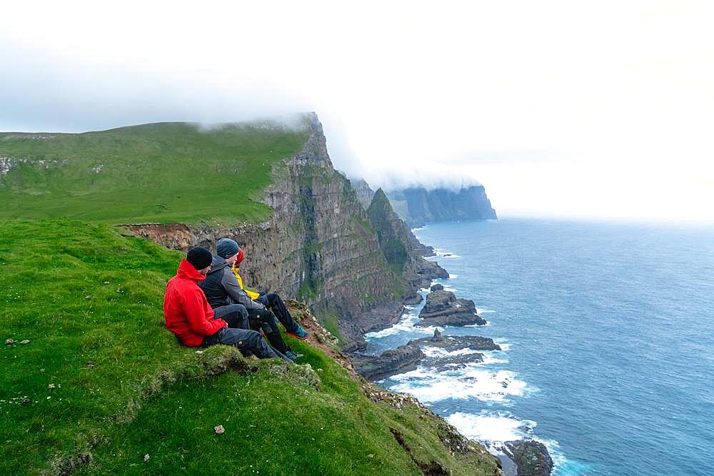 3 Walkers sitting overlooking Beinisforo Cliffs, Sandvik, Suduroy, Faroe Islands, Europe