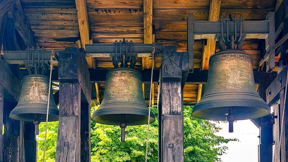 A belfry standing on the ground with four bells of different sizes in the village of Miloradz, Poland, Europe