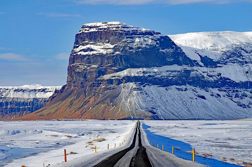 Straight, snow-covered road leading towards a mountain, winter landscape, Lomagnupur, Skeioararsandur, South Iceland, Iceland, Europe