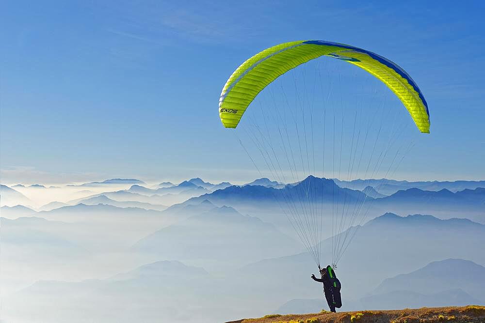 Paraglider taking off with the peaks of the Lake Garda mountains and Bergamo Alps, Monte Baldo, Malcesine, Verona Italy, Trentino-Alto Adige, Italy, Europe