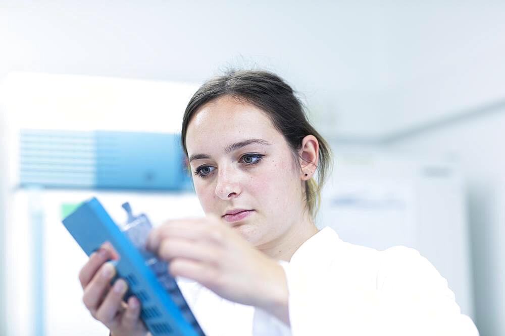 Young laboratory assistant with sample working in a laboratory with laboratory equipment, Freiburg, Baden-Wuerttemberg, Germany, Europe