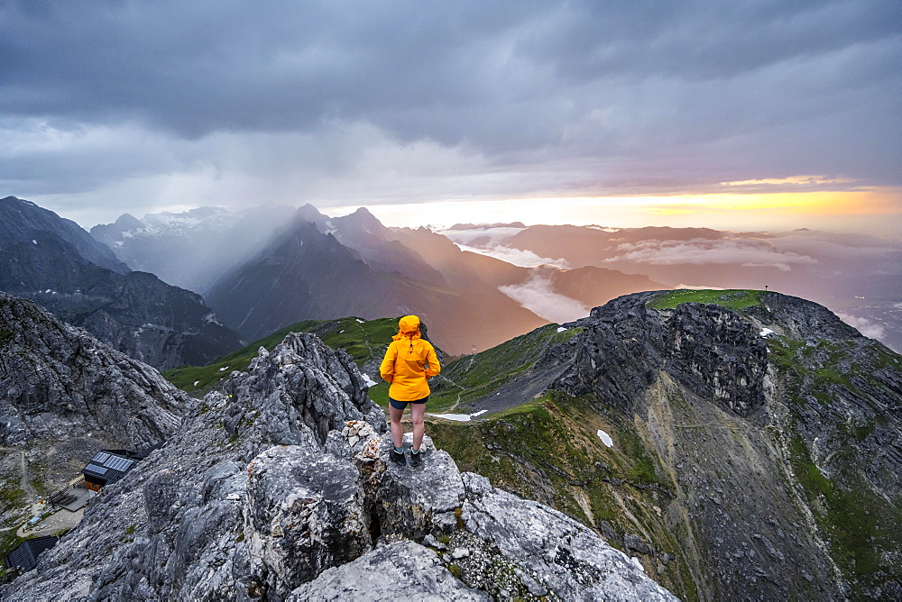 Sunset, hiker looking at mountains and peaks under dramatic clouds, Wetterstein Mountains, Garmisch-Partenkirchen, Bavaria, Germany, Europe