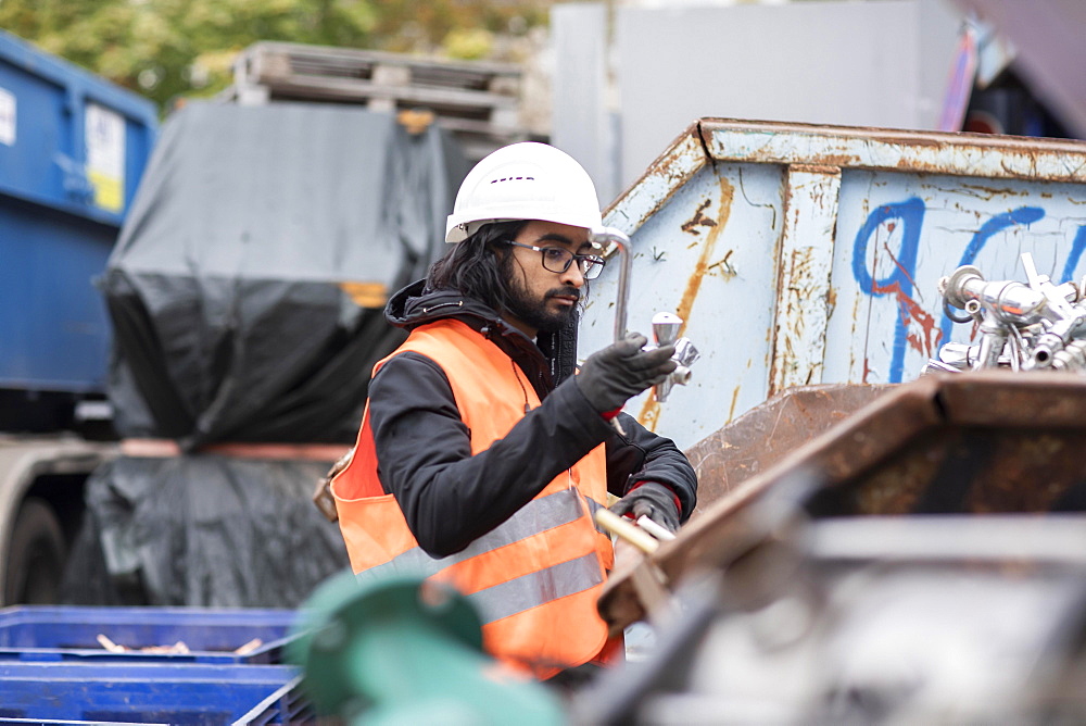 Technician with beard and helmet working in a recycling yard, Freiburg, Baden-Wuerttemberg, Germany, Europe