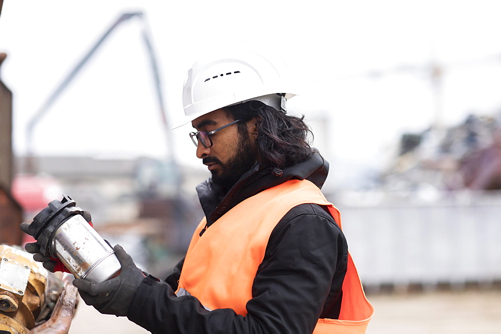 Technician with beard and helmet working in a recycling yard, Freiburg, Baden-Wuerttemberg, Germany, Europe