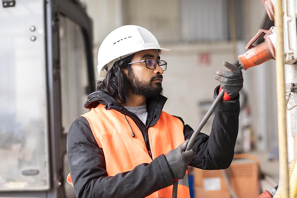 Technician with beard and helmet works in a workshop, Freiburg, Baden-Wuerttemberg, Germany, Europe