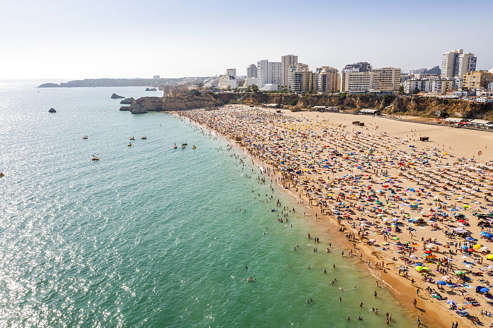 Aerial view of touristic Portimao with wide sandy beach Rocha full of people, Algarve, Portugal, Europe