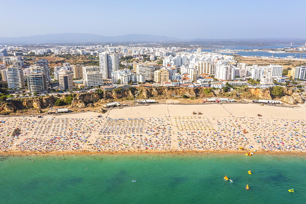 Aerial view of touristic Portimao with wide sandy beach Rocha full of people, Algarve, Portugal, Europe