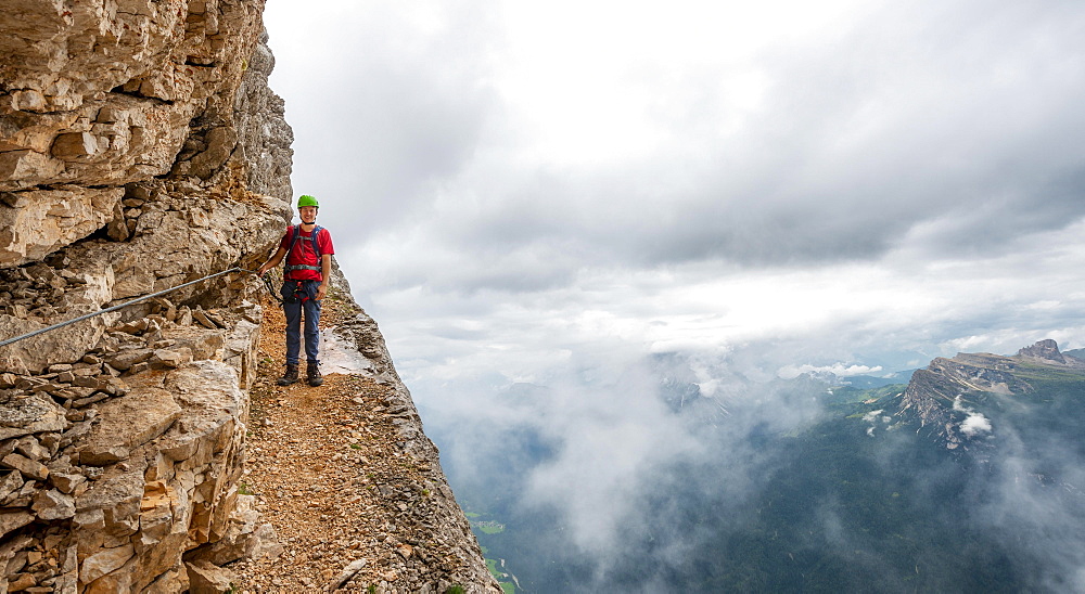 Young man, hiker secured to a steel rope climbing a rock face, Via Ferrata Francesco Berti, Sorapiss circumnavigation, Dolomites, Belluno, Italy, Europe