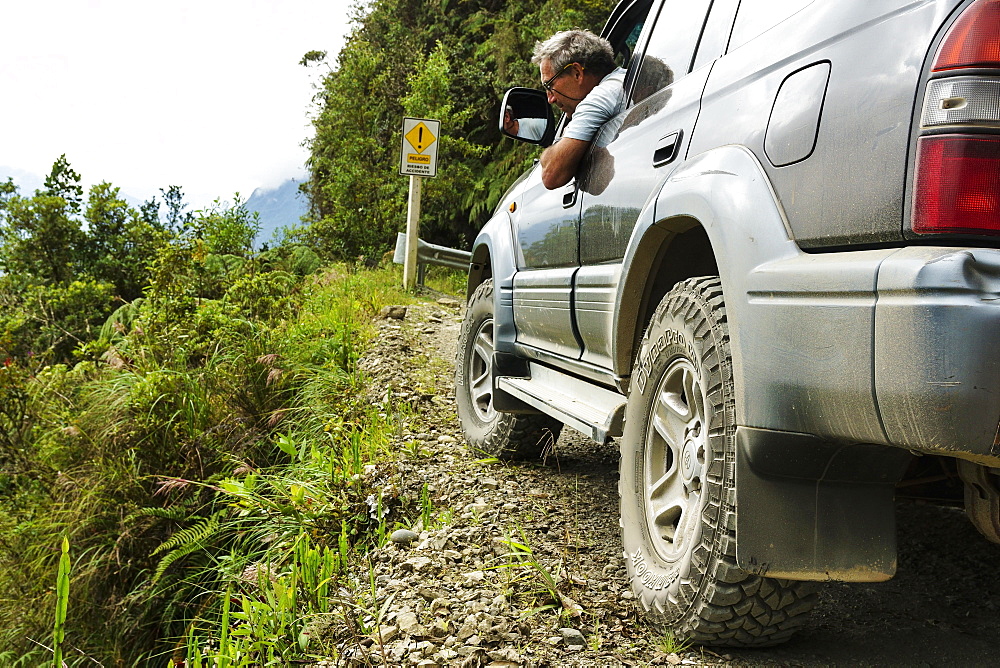 Driver checks the road in an off-road vehicle, Toyota Land Cruiser, on the Death Road, Camino de la Muerte, La Paz Department, Bolivia, South America