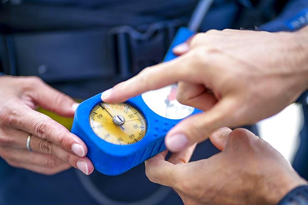 Man explaining that pressure gauge shows how much air is in the tank during scuba diving, Spain, Europe