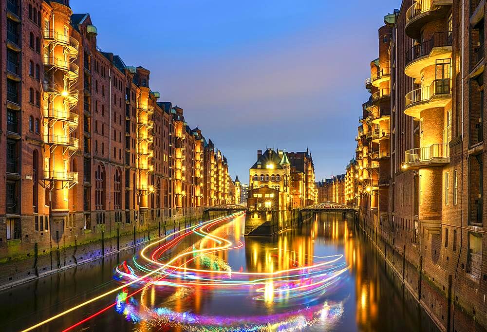 Night shot of the moated castle and an excursion ship with fairy lights in the Speicherstadt, Hamburg, Germany, Europe