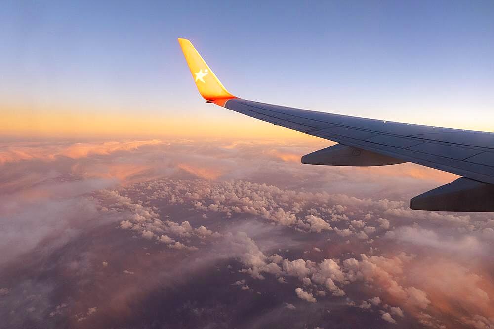 Aeroplane wing, flight over cloud cover, sunset