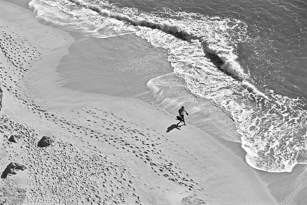 Man with guitar on lonely beach with footprints in sand, from above, Algave, Portugal, Europe