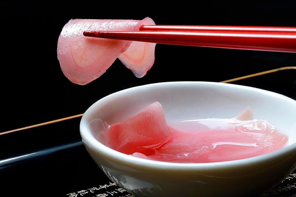 Sliced pickled ginger on chopsticks and in bowl