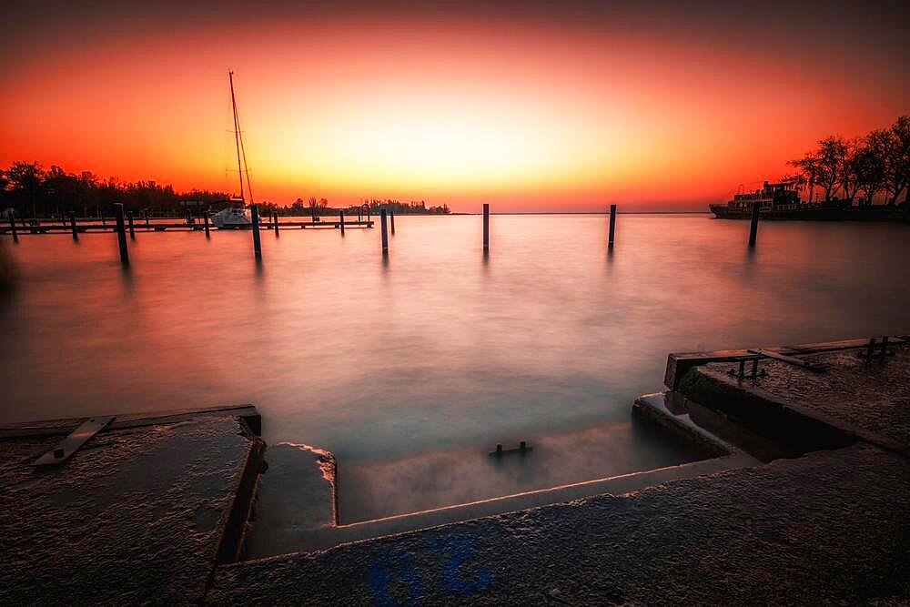 Harbour at a lake, with boat and mooring. In the background the sun rises, long exposure, Balatonfuered, Balaton, Lake Balaton, Hungary, Europe