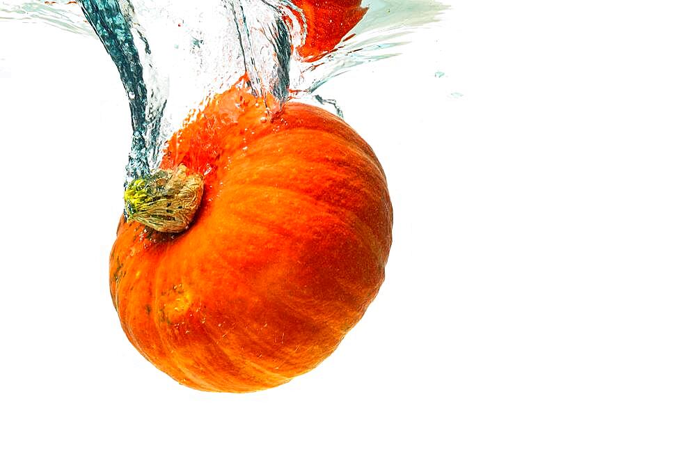 Orange pumpkin splashing into water isolated against white background, Healthy vegetables concept