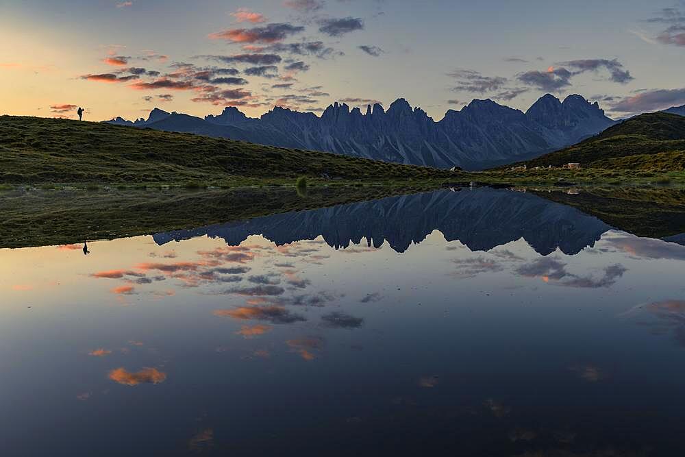 Salfainsee with reflection of the Kalkkoegel and mountaineers on mountain meadow at sunrise, Sellrain, Innsbruck, Tyrol, Austria, Europe