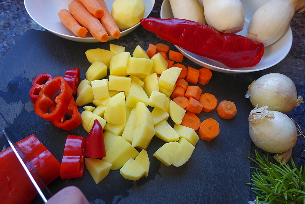 Southern German cuisine, preparing vegetables from the Roman pot, cutting vegetables, red peppers, carrots, diced potatoes, onions, knife, chopping board, rosemary, Germany, Europe