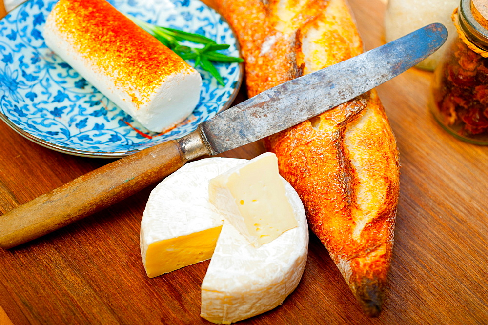 French cheese and fresh baguette on a wood cutter