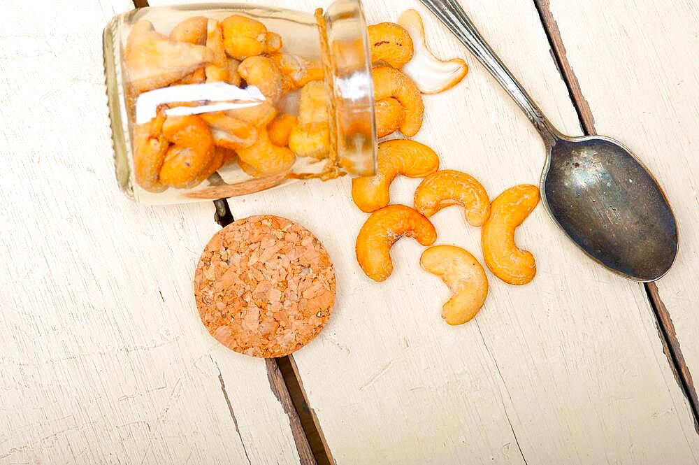 Cashew nuts on a glass jar over white rustic wood table