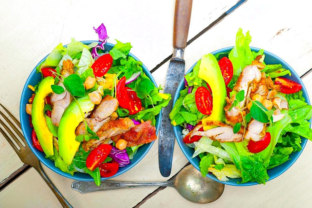 Fresh and healthy Chicken Avocado salad over rustic wood table