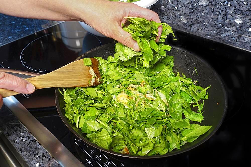 Swabian cuisine, sauteing spinach in a pan, preparing spinach pie spoon style, Swabian speciality, men's hands, spatula, Germany, Europe