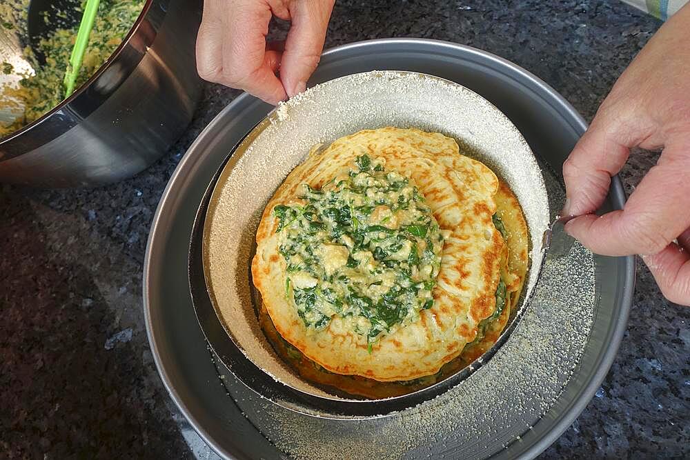 Swabian cuisine, pancakes, pancake layers with spinach mixture, springform pan, cake tin, preparing spinach cake spoon style, Swabian speciality, men's hands, Germany, Europe