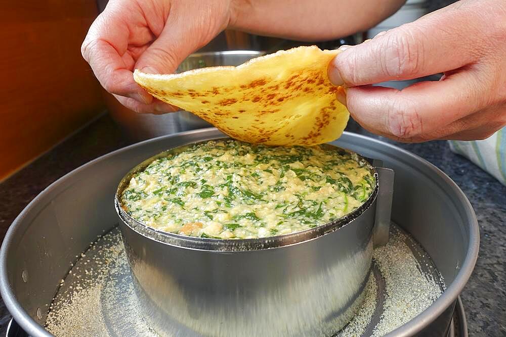 Swabian cuisine, pancakes, pancake layers with spinach mixture, springform pan, cake tin, preparing spinach cake spoon style, Swabian speciality, men's hands, Germany, Europe