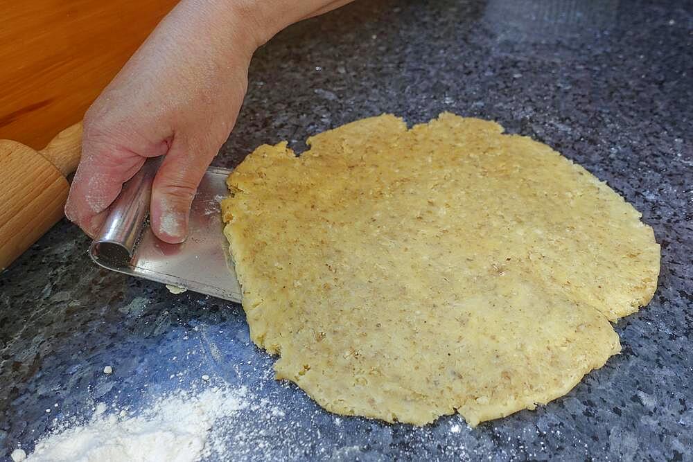 Southern German cuisine, baking, preparing the walnut dough for the hearty vegetable cake with walnut base, working the dough, man's hand, dough scraper, Germany, Europe