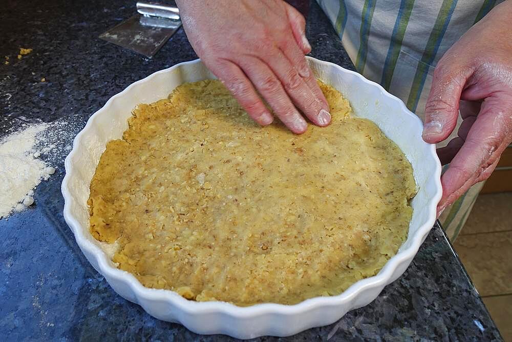 Southern German cuisine, baking, preparing hearty vegetable cake with walnut base, pressing walnut dough into the baking tin, tart tin, quiche tin, working the dough, men's hands, Germany, Europe