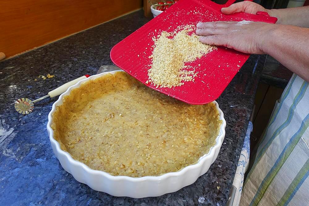 Southern German cuisine, baking, preparation of hearty vegetable cake with walnut base, walnut dough in the baking tin, tart tin, quiche tin, pastry wheel, men's hands, Germany, Europe