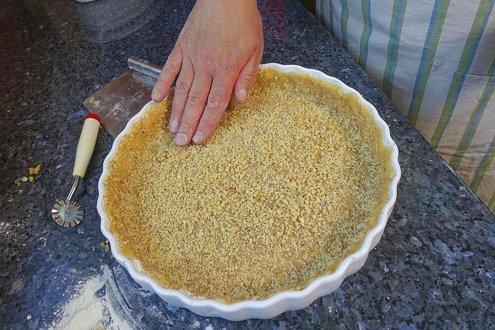 Southern German cuisine, baking, preparation of hearty vegetable cake with walnut base, walnut dough in the baking tin, tart tin, quiche tin, pastry wheel, man's hand, Germany, Europe