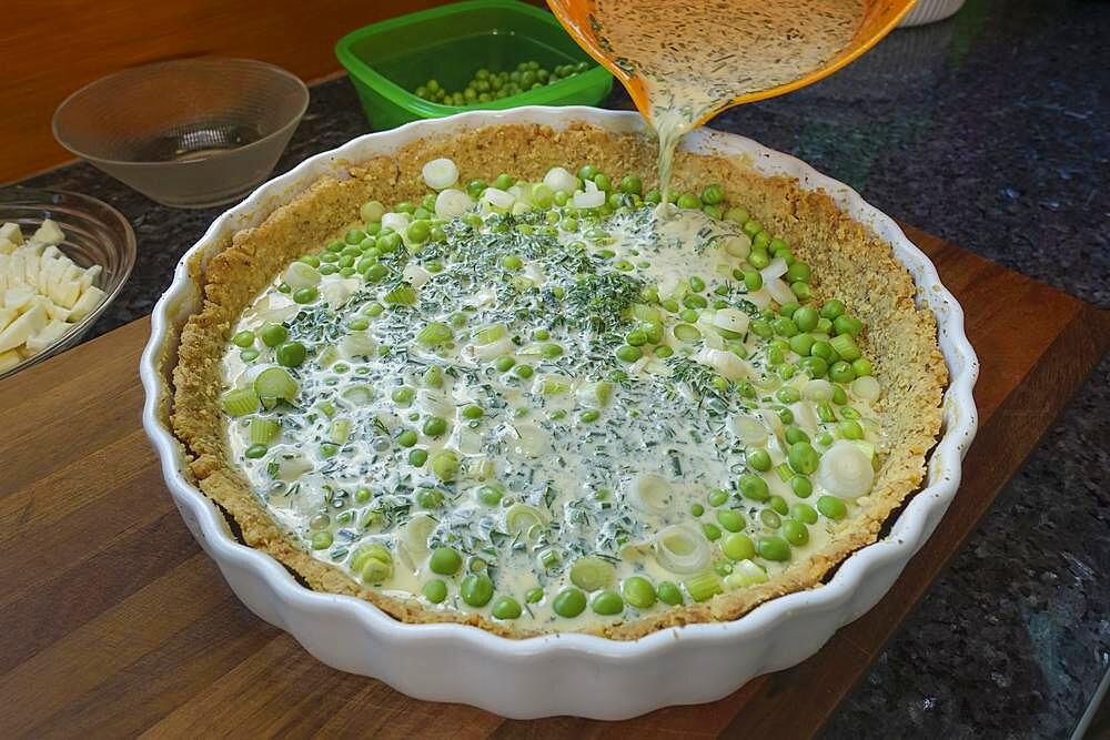 Southern German cuisine, baking, preparing hearty vegetable tart with walnut base, walnut dough in baking tin, dough with green peas, spring onions, filling mass into tart tin, quiche tin, mixing bowl, Germany, Europe