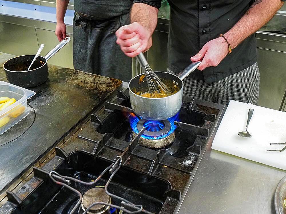 Chef using a hand mixer making a potato sauce cream reduction in a professional kitchen of a restaurant, gourmet professional cooking concept