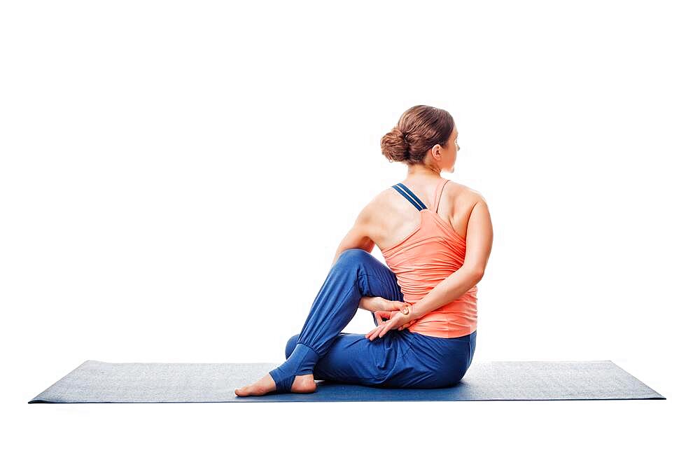 Beautiful sporty fit woman practices yoga asana Ardha matsyendrasana, half spinal twist pose isolated on white