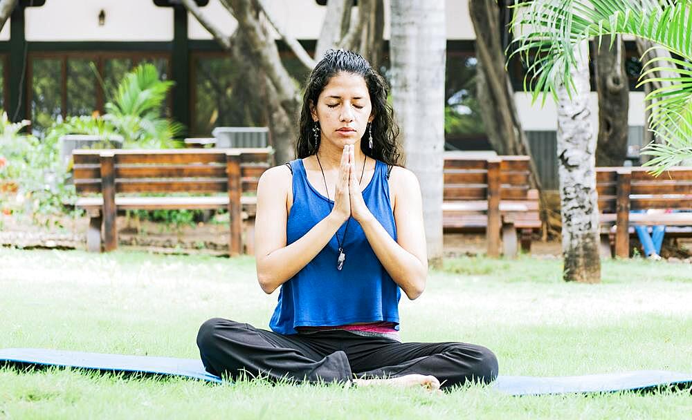 A girl sitting doing meditation yoga outdoors, Woman doing yoga outdoors, a young woman doing yoga with closed eyes