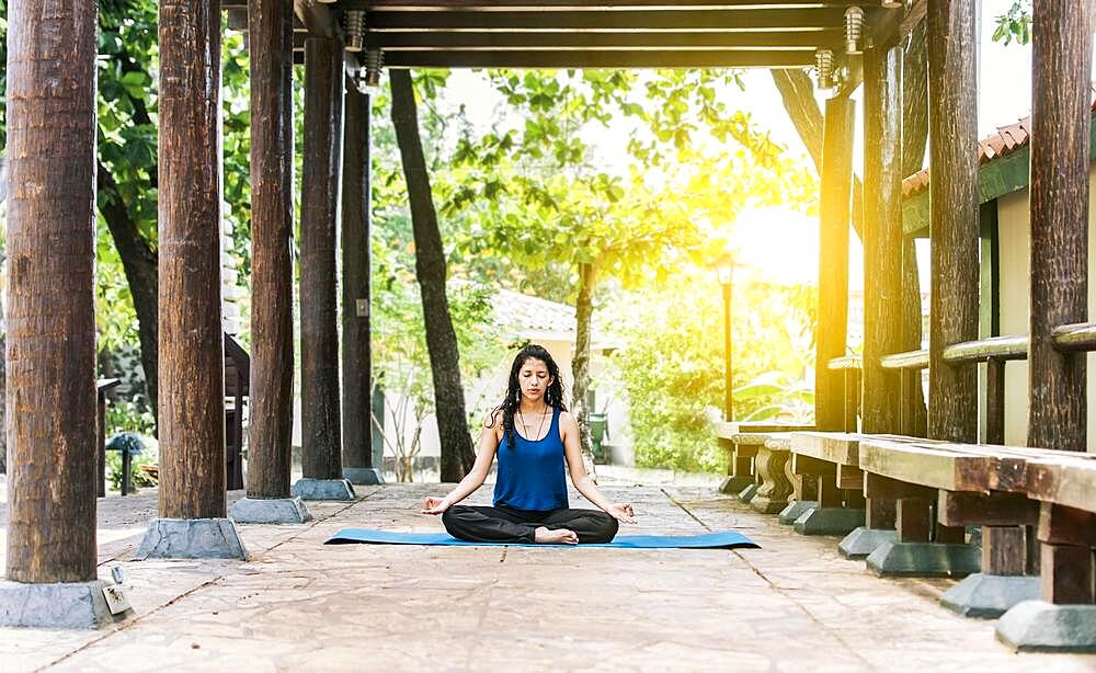 A girl sitting doing meditation yoga outdoors, Woman doing yoga outdoors, a young woman doing yoga with closed eyes