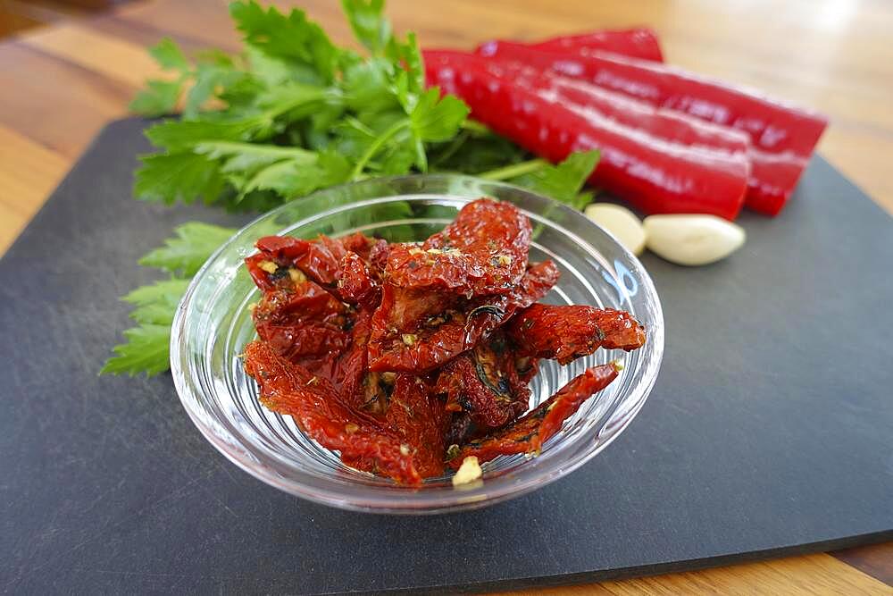 Swabian cuisine, preparation of hearty Gugelhupf, dried tomatoes in oil, red peppers at the back, large-leaf parsley, garlic cloves on chopping board, kitchen board, wooden plate, vegetarian, vegetables, healthy, typical Swabian reinterpreted, traditional cuisine, food photography, studio, Germany, Europe