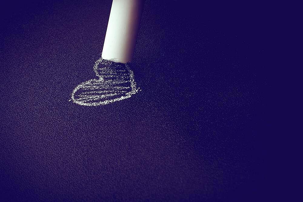 Hand holding white chalk and black board