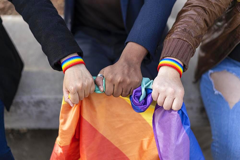 Multi ethnic lgbt gruup wearing lgbt wristbands, holding lgbt flag