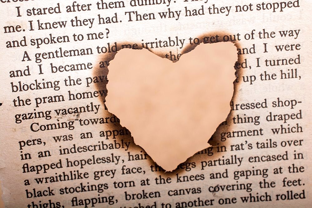 Heart shaped burnt out of a texted paper