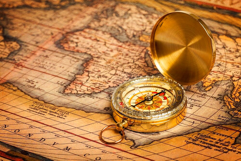 Old vintage retro golden compass on ancient map