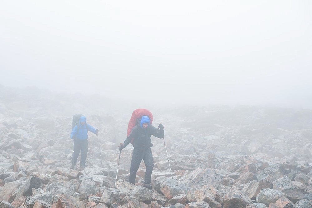 2 men with trekking equipment in rocky landscape, fog, rain, West Greenland, Greenland, North America