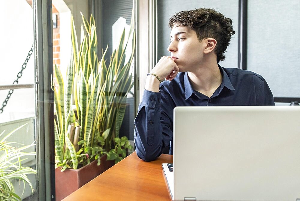 Young thoughtful man in the office looking through the window