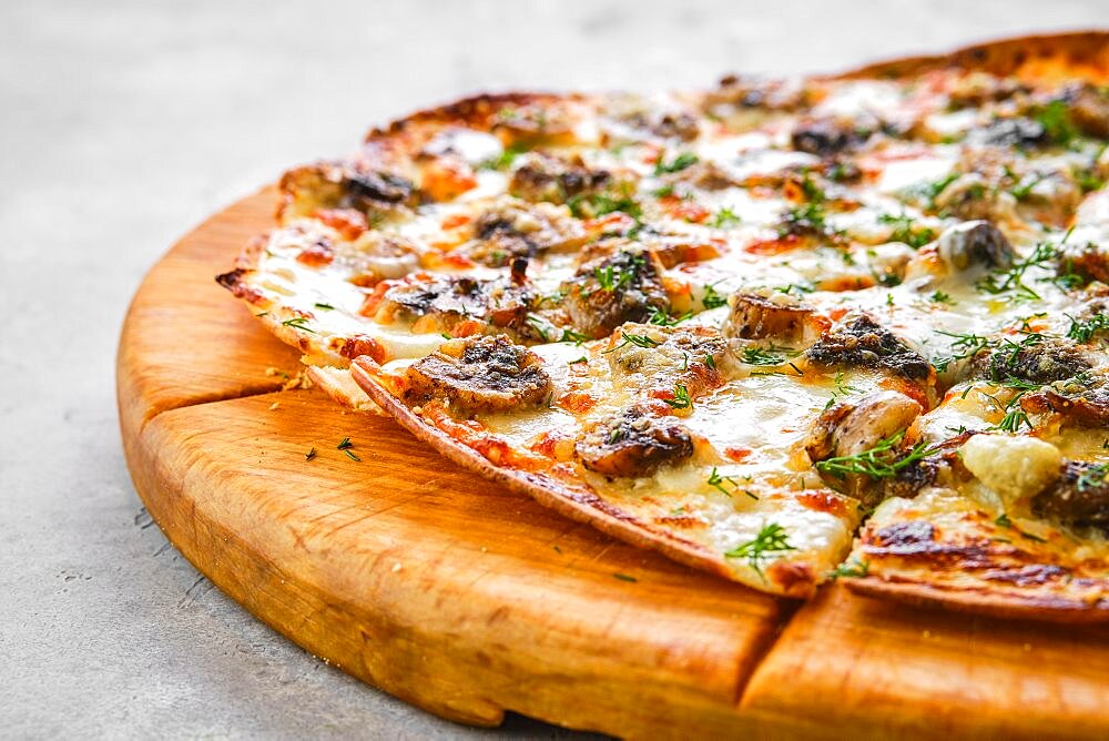 Thin-crust pizza dough with mushrooms and lot of melted cheese (closeup photo with shallow depth of field)