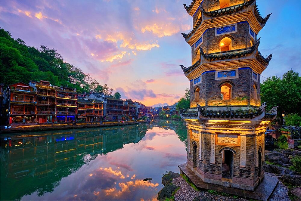 Chinese tourist attraction destination, Feng Huang Ancient Town (Phoenix Ancient Town) on Tuo Jiang River with Wanming Pagoda illuminated at night. Hunan Province, China, Asia