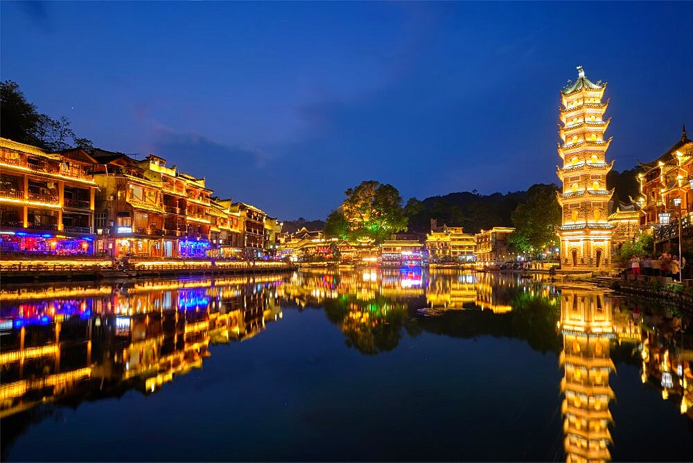 Chinese tourist attraction destination, Feng Huang Ancient Town (Phoenix Ancient Town) on Tuo Jiang River with Wanming Pagoda illuminated at night. Hunan Province, China, Asia